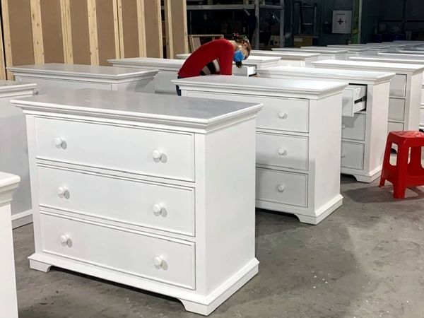 Inspector checking drawers of white nursery dressers before packing