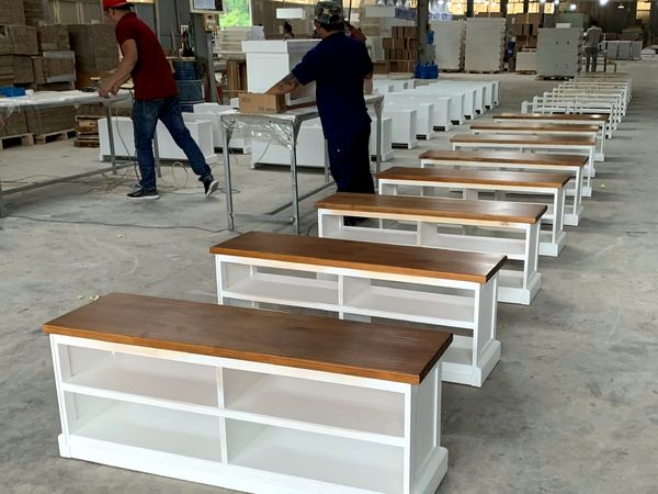 Workers assembling solid-wood TV benches on the production line